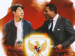 Shin Tae-yong bersama salah satu perwakilan Timnas Indonesia, dengan latar belakang lambang Garuda.