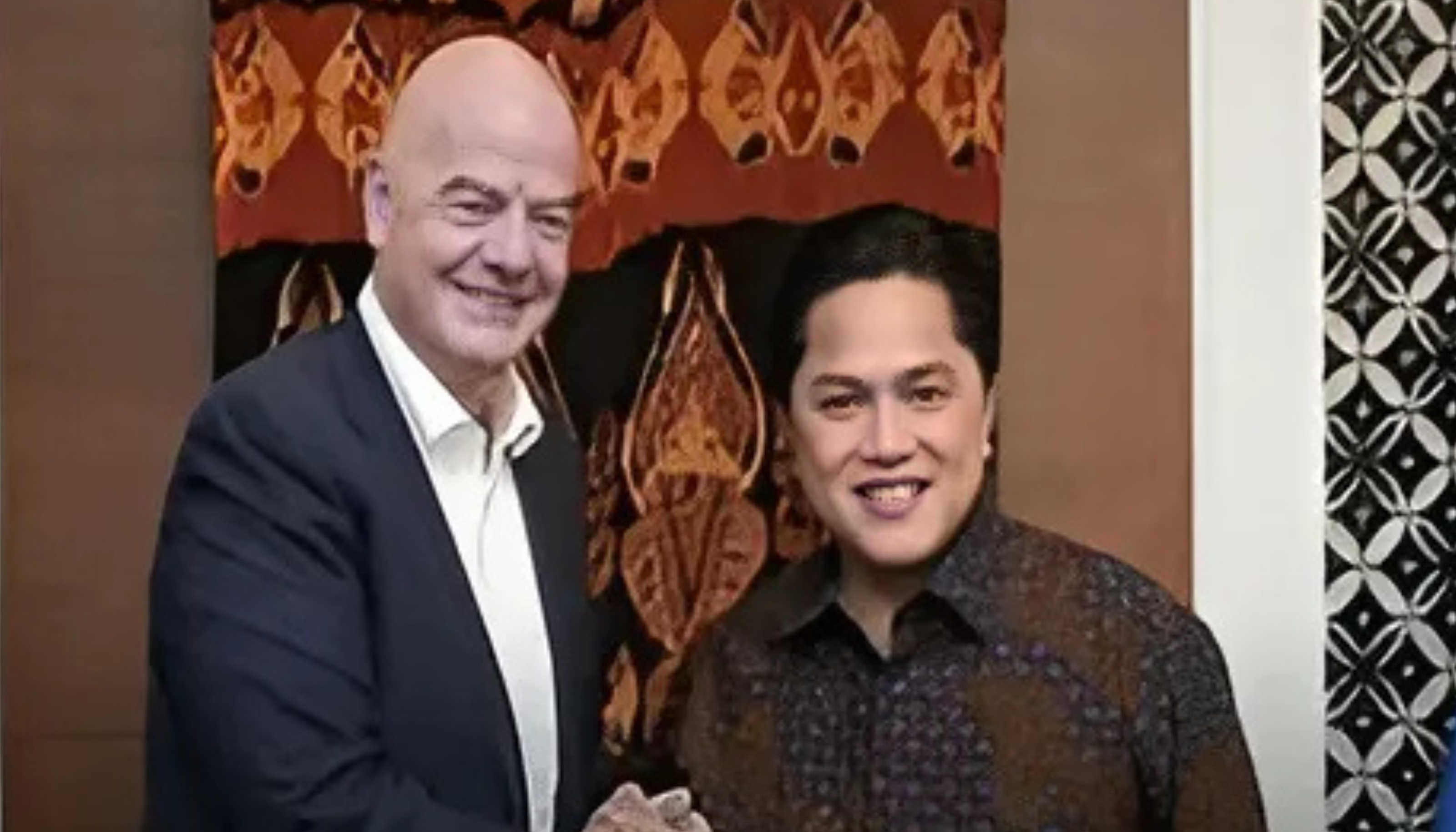 Erick Thohir bersama seorang pejabat dalam pertemuan resmi, tersenyum ke arah kamera