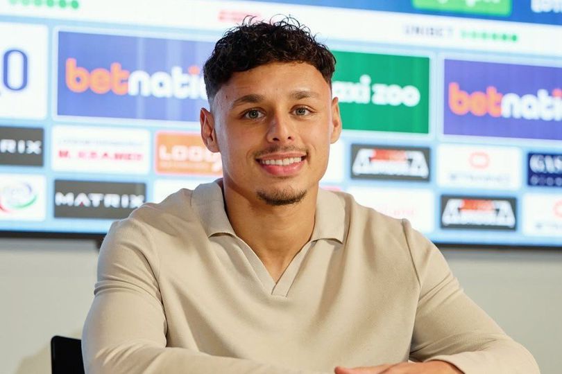 Dean James, pemain Go Ahead Eagles, mengenakan jersey klub dengan latar belakang ruangan yang sederhana.