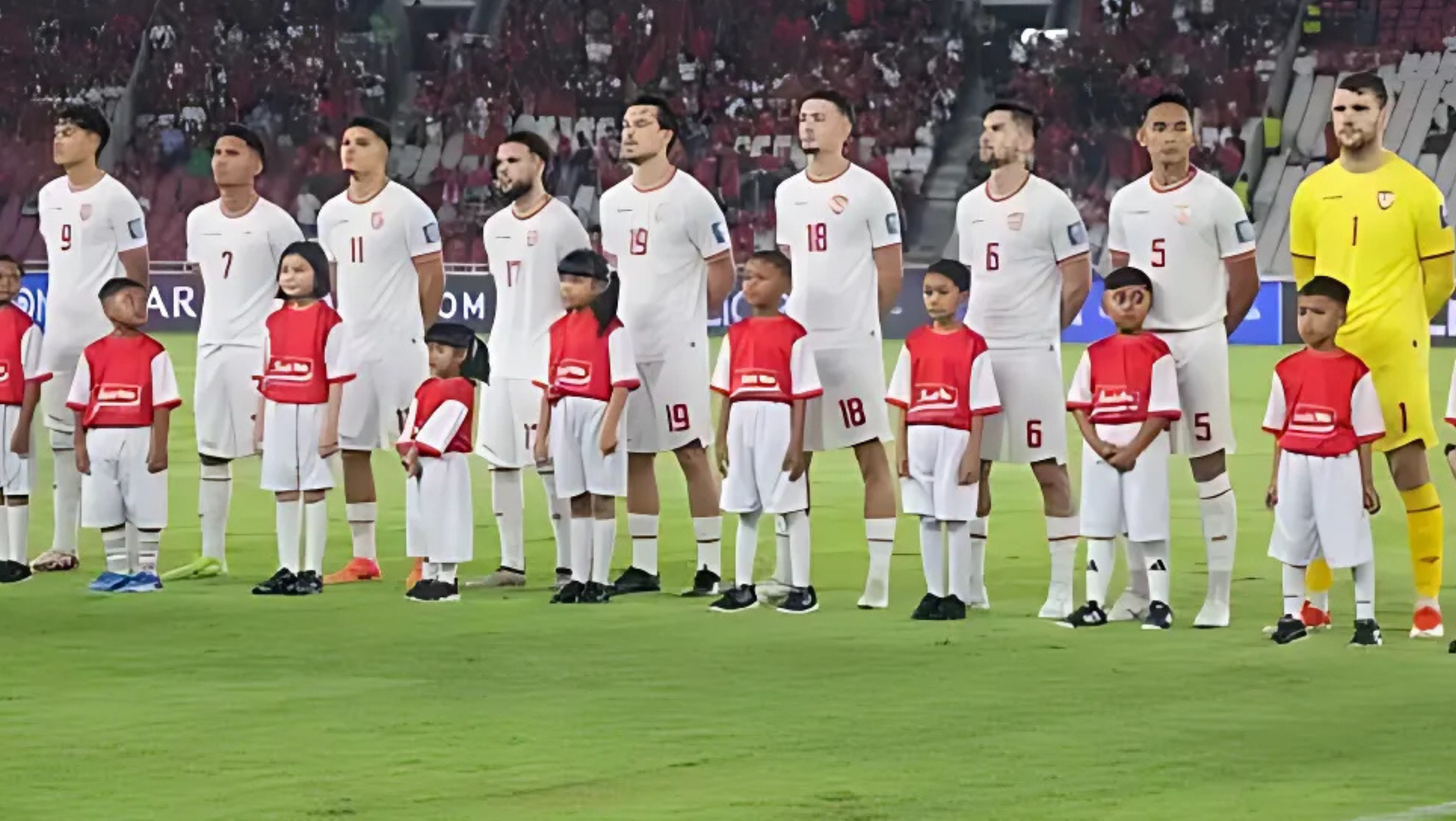 Timnas Indonesia berbaris sebelum pertandingan, mengenakan seragam merah dan putih di lapangan sepak bola