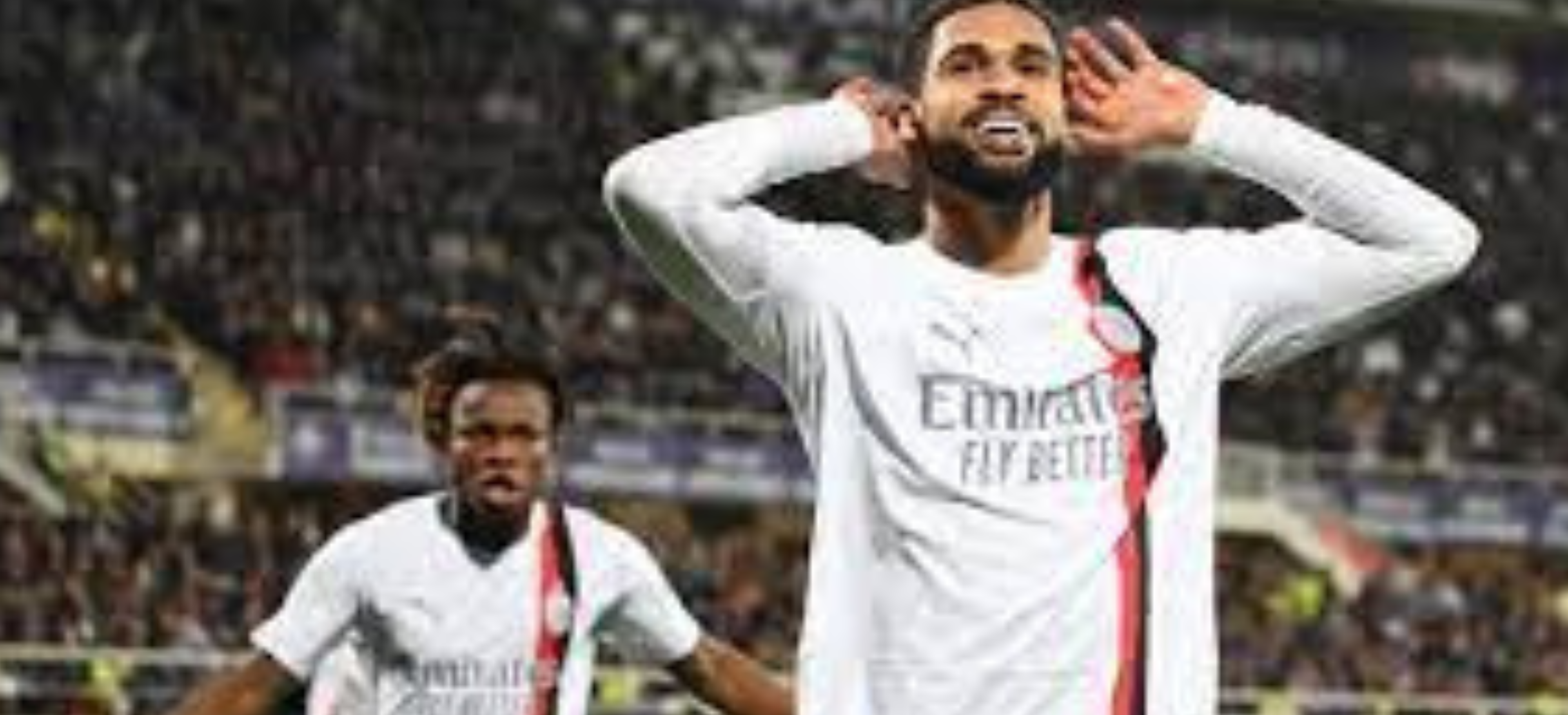 Seorang pemain sepak bola mengangkat tangan ke udara saat merayakan gol di tengah lapangan."