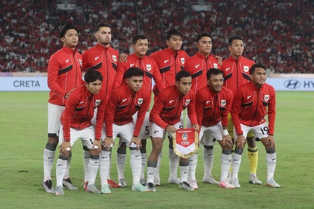 "Diagram taktik formasi 4-3-3 Timnas Indonesia U-23 dengan posisi pemain: Ernando (kiper), Komang Teguh-Rizky Ridho (bek tengah), Haykal-Frengky (bek sayap), Adam Alis-Arkan Fikri-Marselino (gelandang), Struick-Hokky-Sroyer (penyerang). Latar belakang grafis lapangan hijau dengan logo Piala Asia U-23 2026."